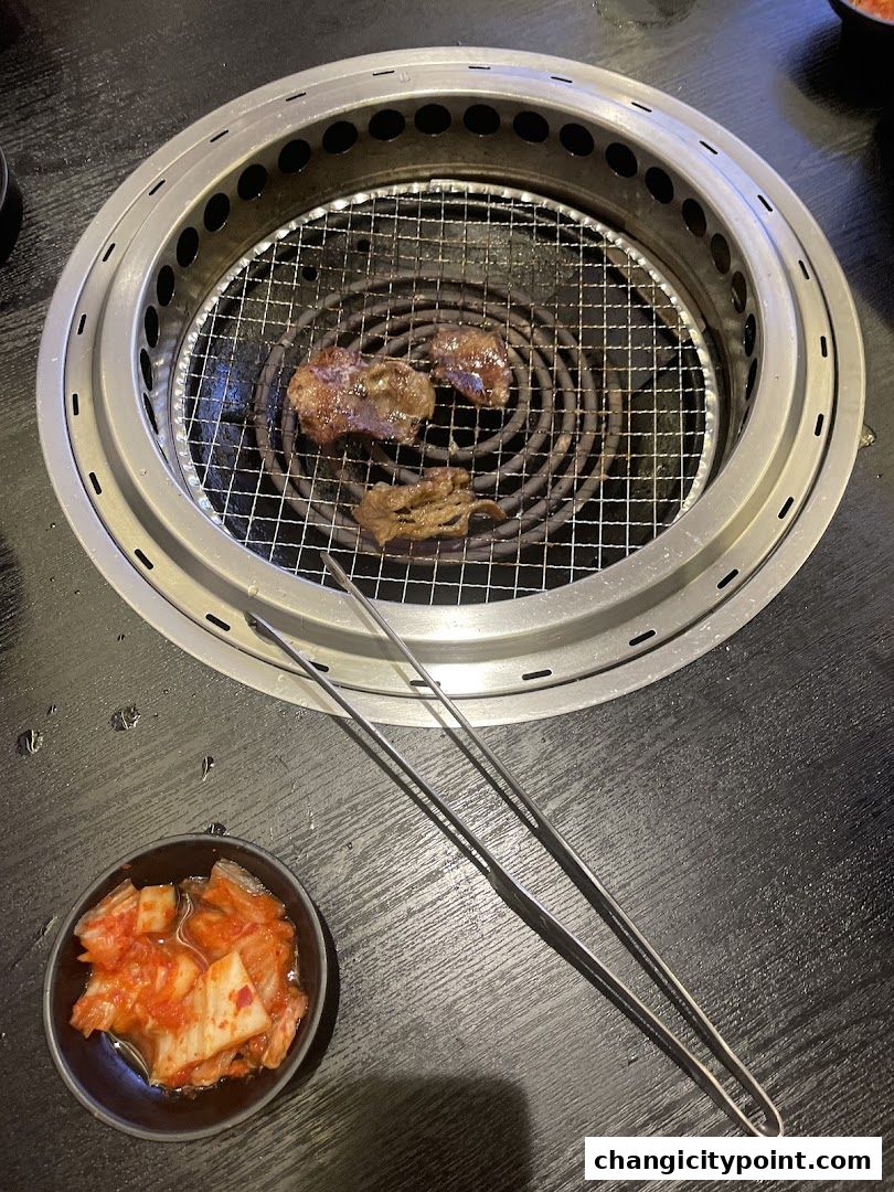 Grilling meat on a yakiniku grill with a side of kimchi.