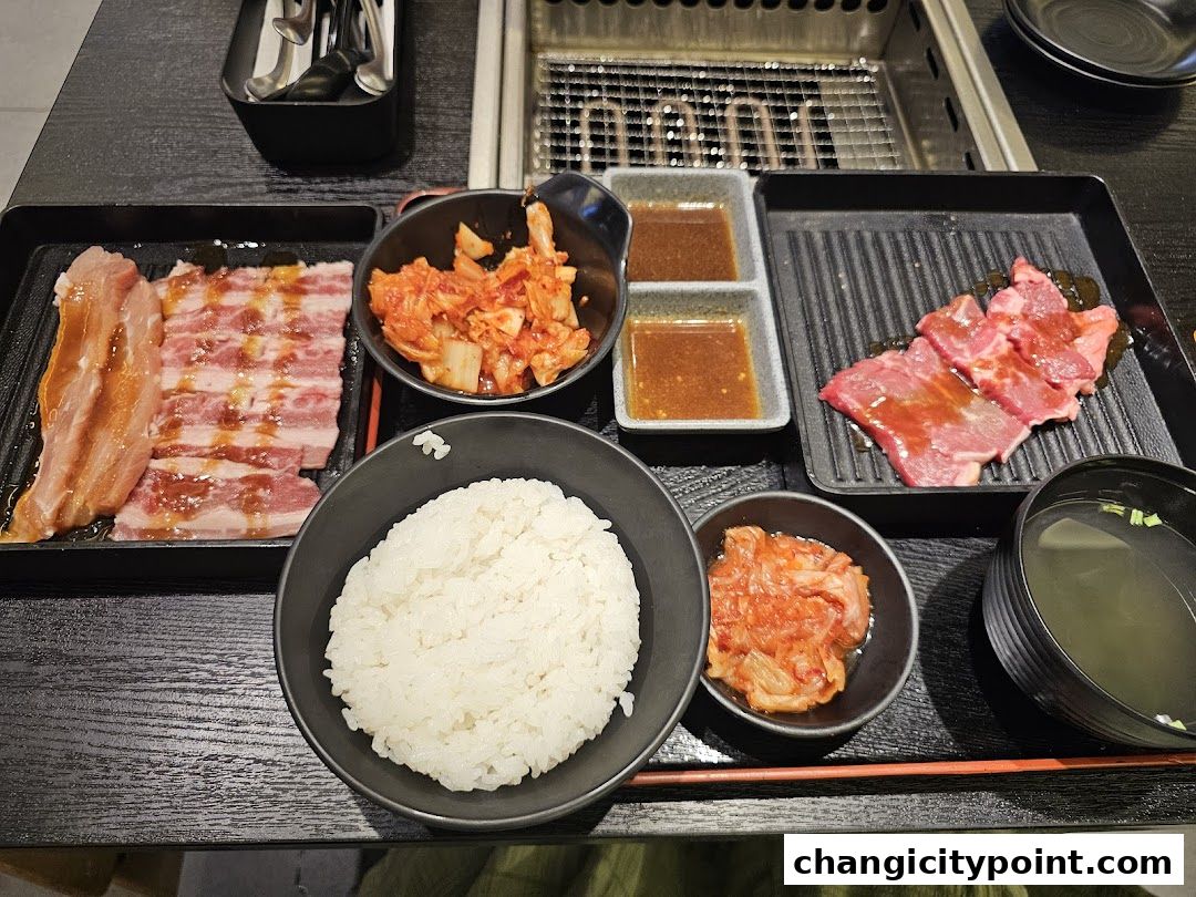 A delicious spread of grilled meats, rice, kimchi, and soup, ready for a meal.