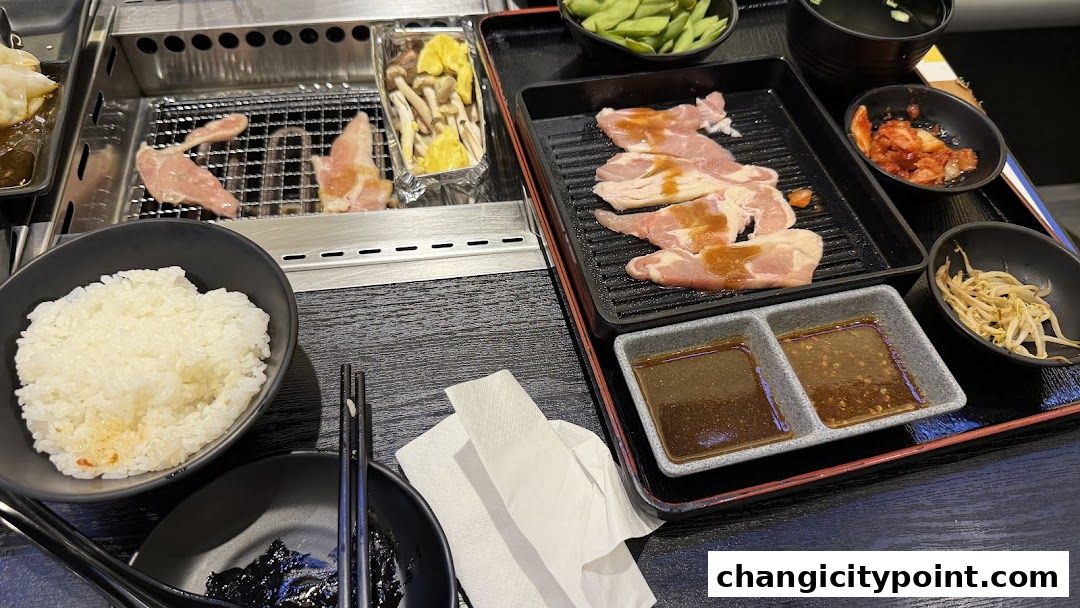 A table set for a yakiniku meal with grilled meats, rice, and side dishes.