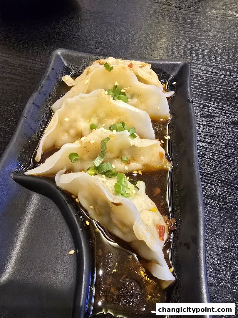 A plate of delicious pan-fried dumplings with a savory sauce and green onions.