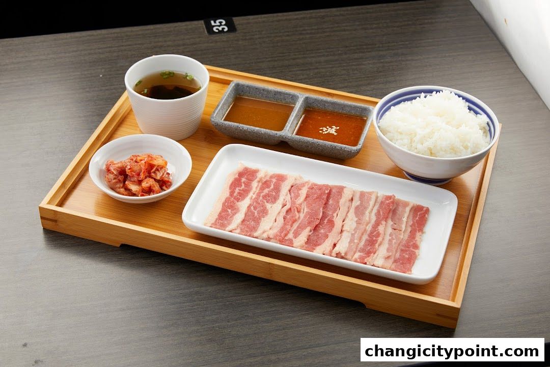 A tray with thinly sliced raw beef, rice, kimchi, soup, and dipping sauces.