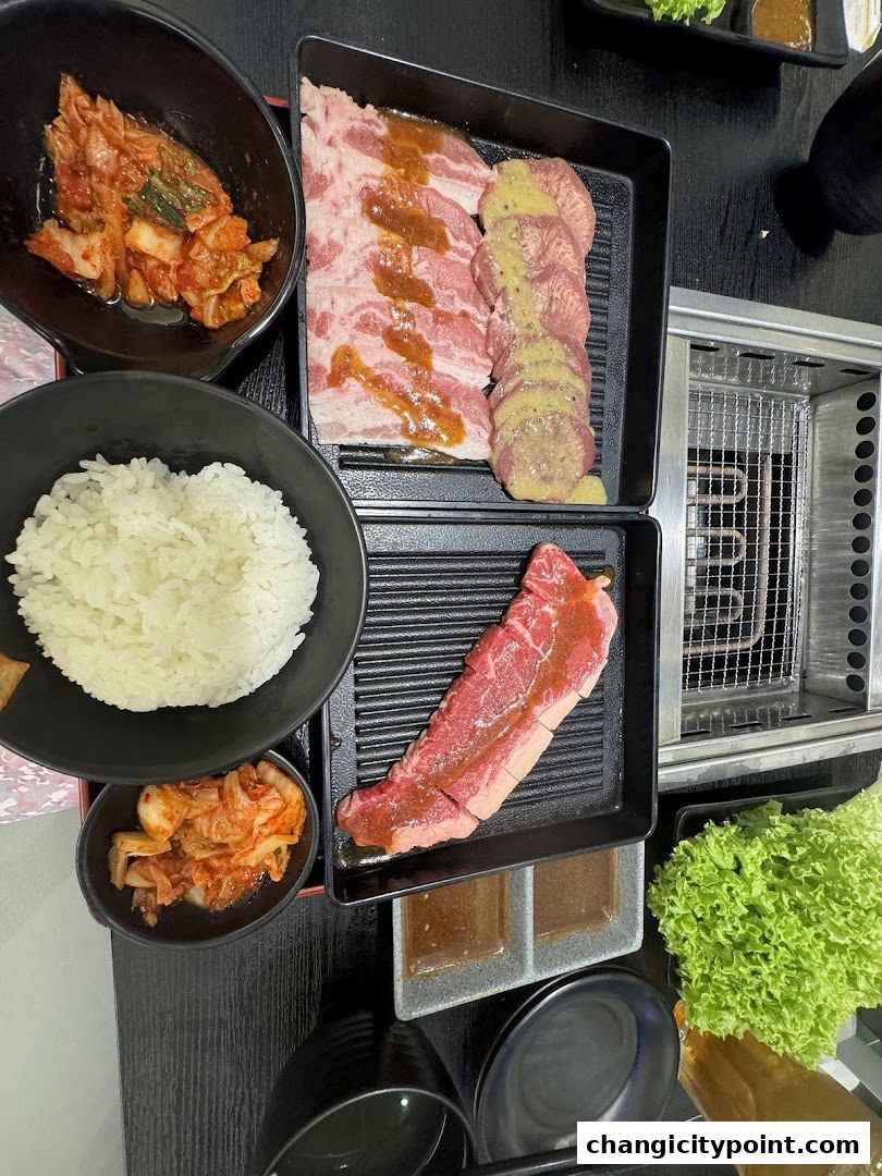 A table laden with grilled meats, rice, kimchi, and lettuce, ready for a yakiniku feast.