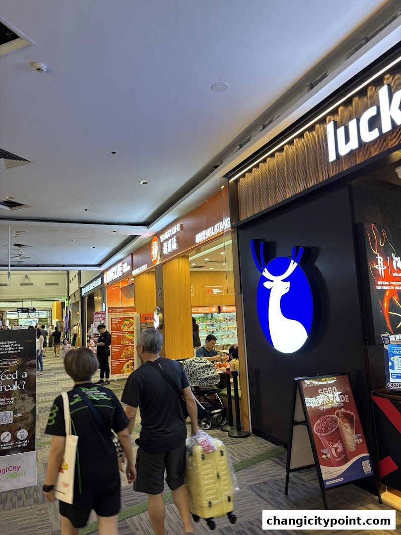 People walk past a Yang Guo Fu Mala Tang shop and a Luckin Coffee store in a mall.