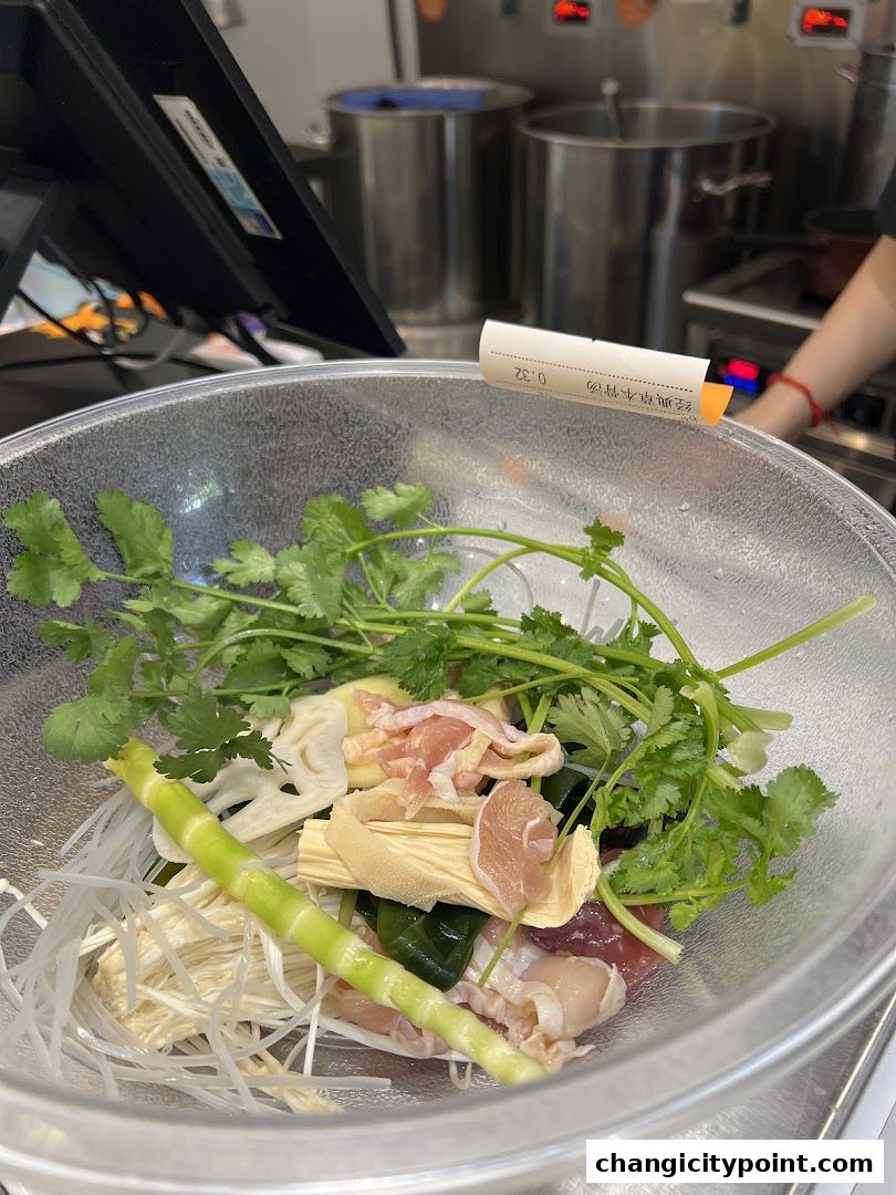 A bowl of fresh ingredients for Mala Tang, including meat, vegetables, and noodles.