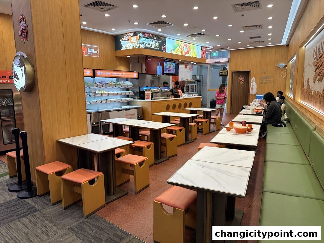 Interior of a Yang Guo Fu Mala Tang restaurant with tables, seating, and food display.