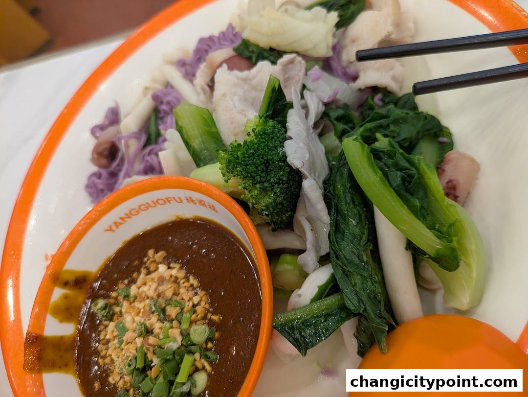 A bowl of Mala Tang with various vegetables and meat, served with dipping sauce.